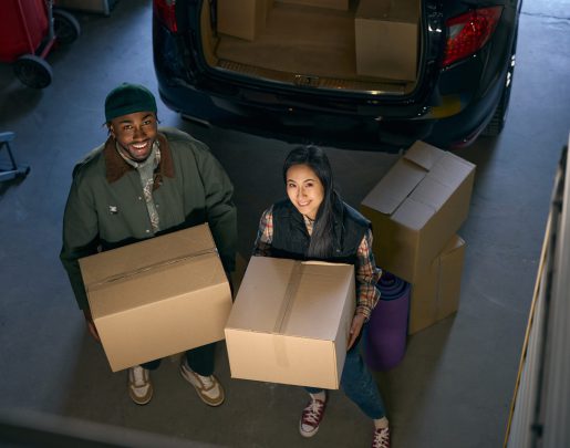 Young male and a female are standing in a storage service holding a box in their hands